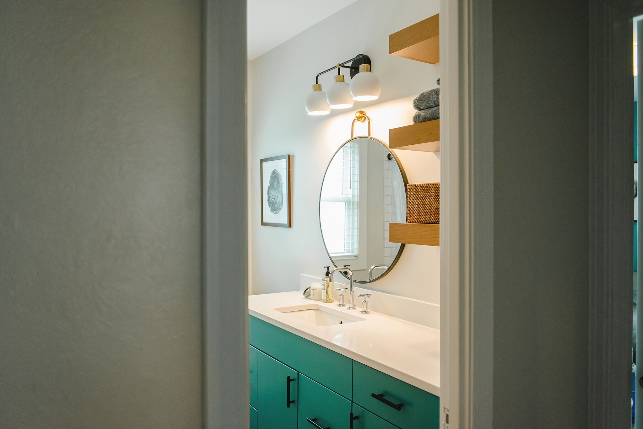 Teal mid-century modern bathroom vanity with white countertops and custom floating shelves