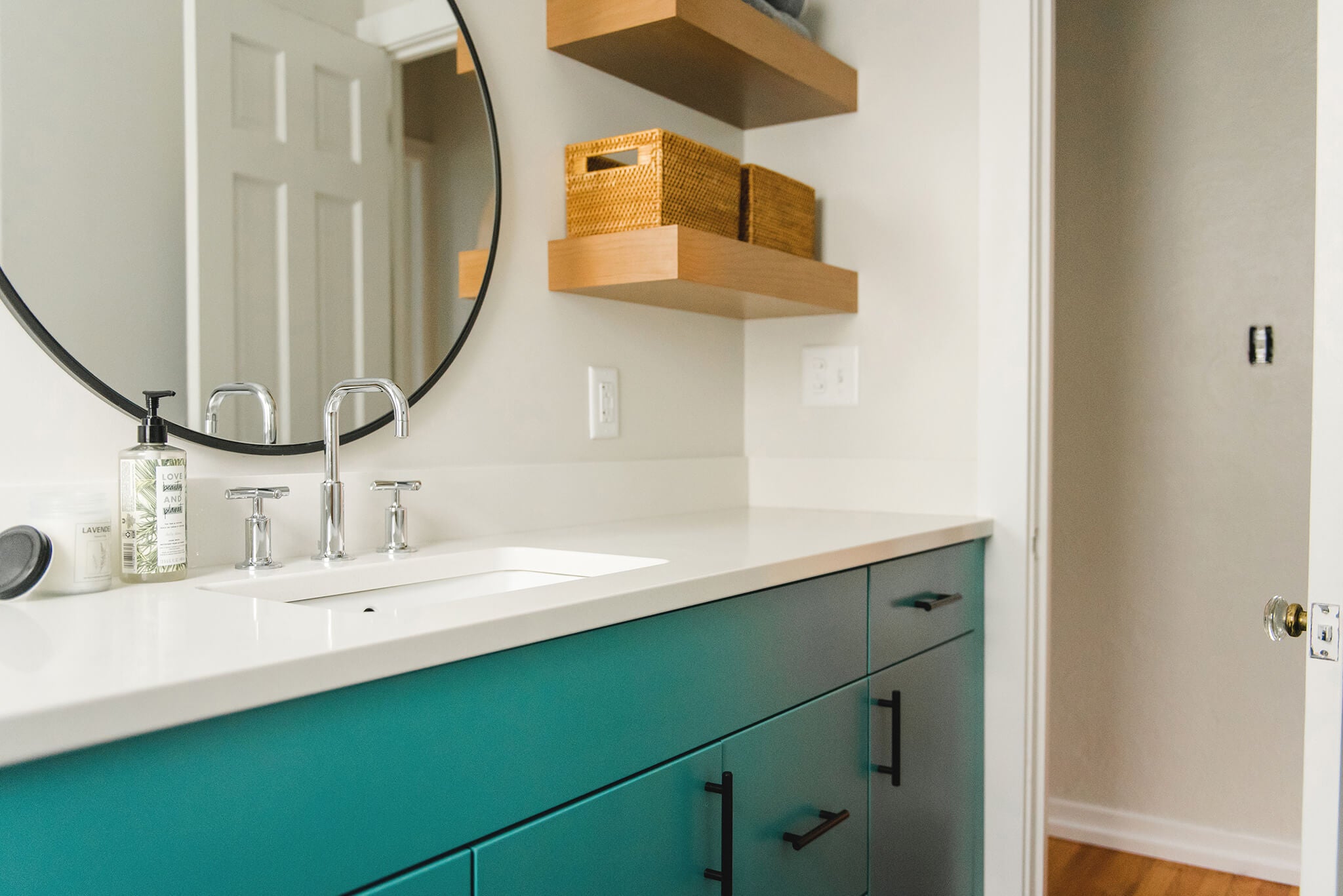 Teal mid-century modern bathroom vanity with white countertops and custom floating shelves