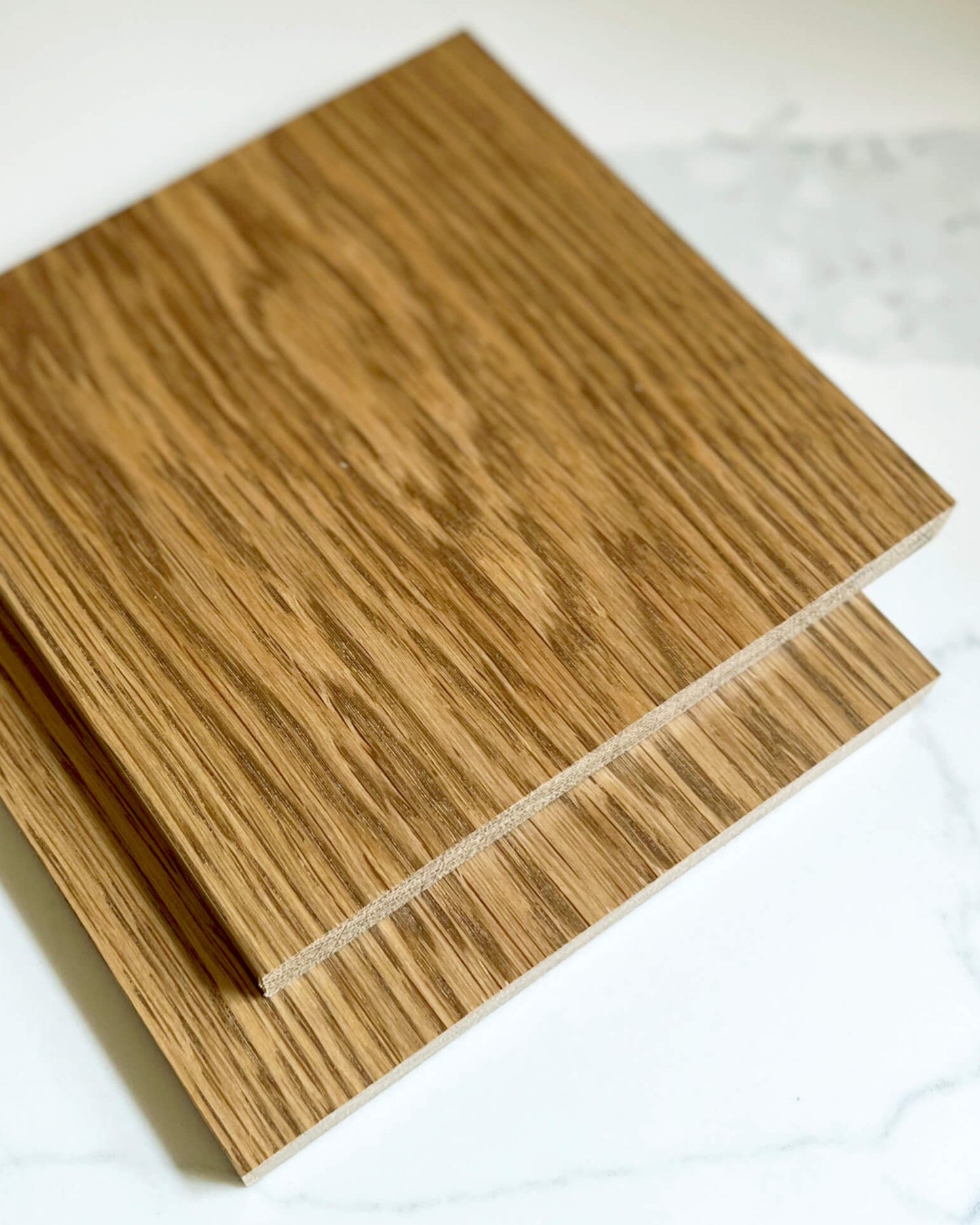 Two wooden oak stain samples on a white marble surface
