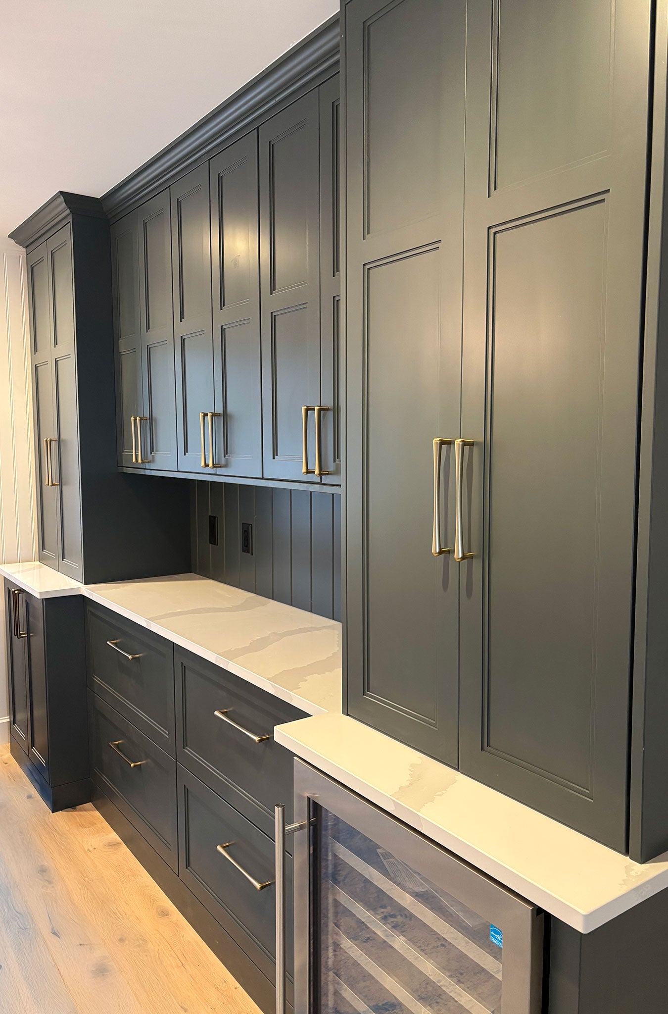 Modern built-in kitchen buffet with dark green cabinets and light countertops.