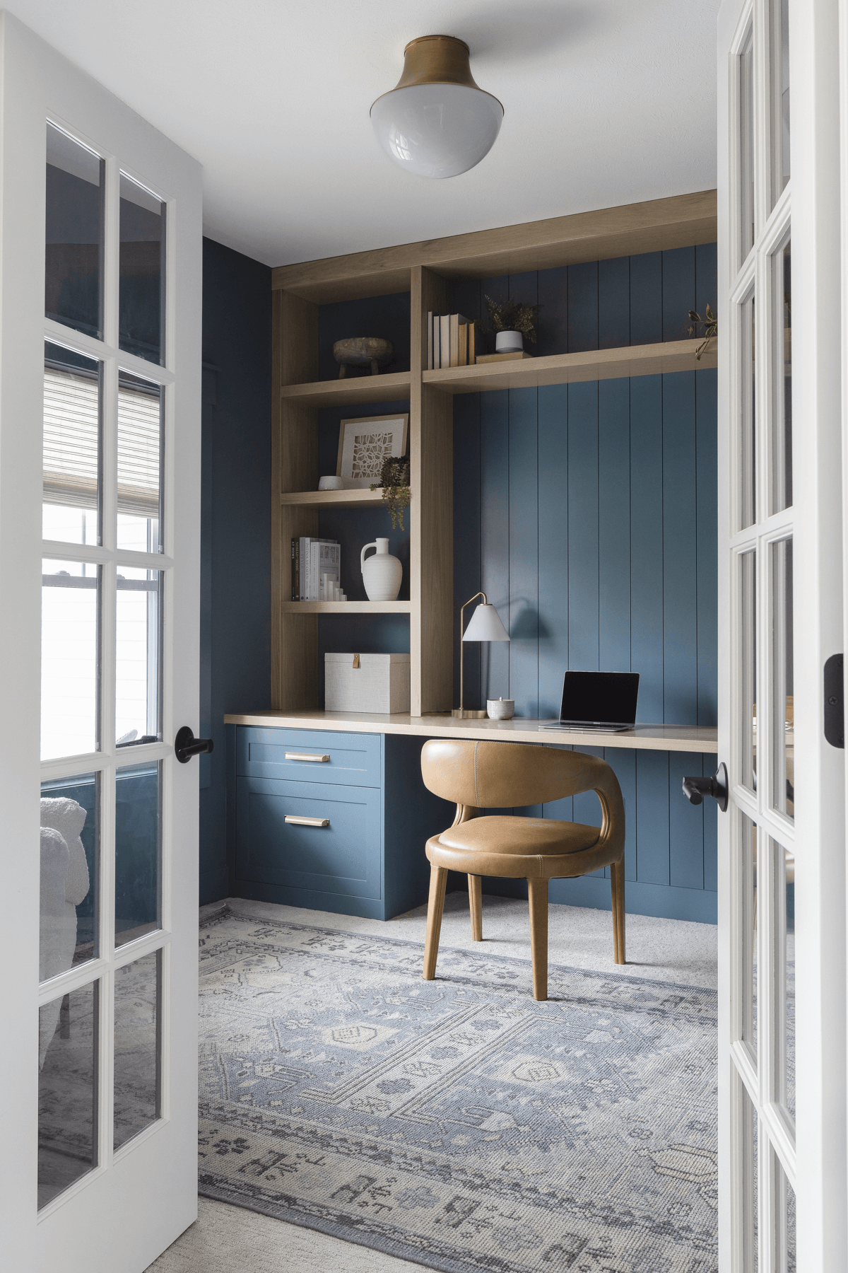 Small home office with built-in blue cabinetry and light wood open shelving.