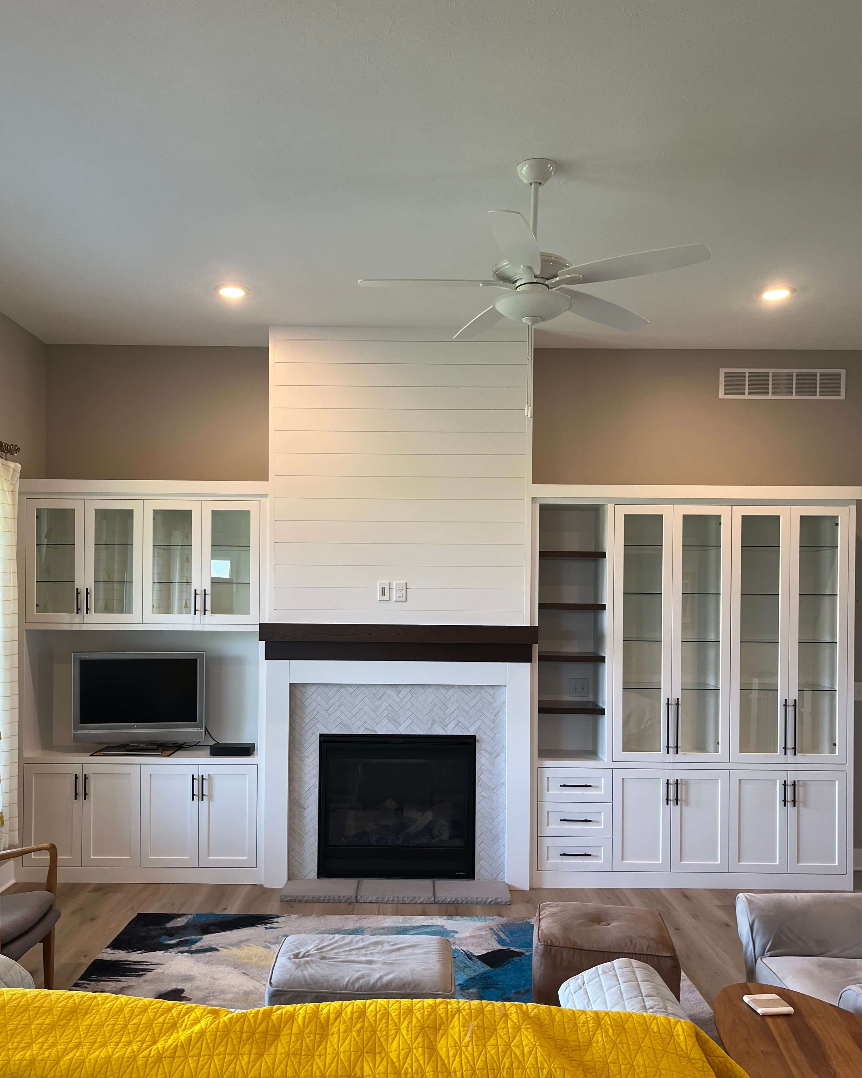 Living room with white shiplap fireplace and a custom entertainment center, featuring a television and decorative items.